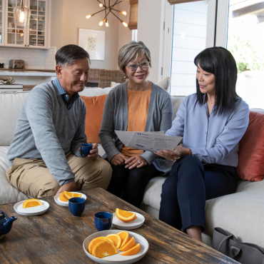 As Asian woman shows her retirement-age participants some printed materials that have been translated into their language.